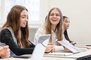 Lachende Studentin mit Laptop in einem Seminar